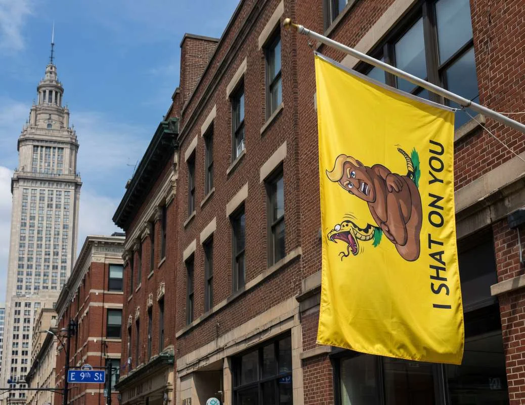 Yellow flag on a downtown building with turd-snake character; text 'I Shat On You'